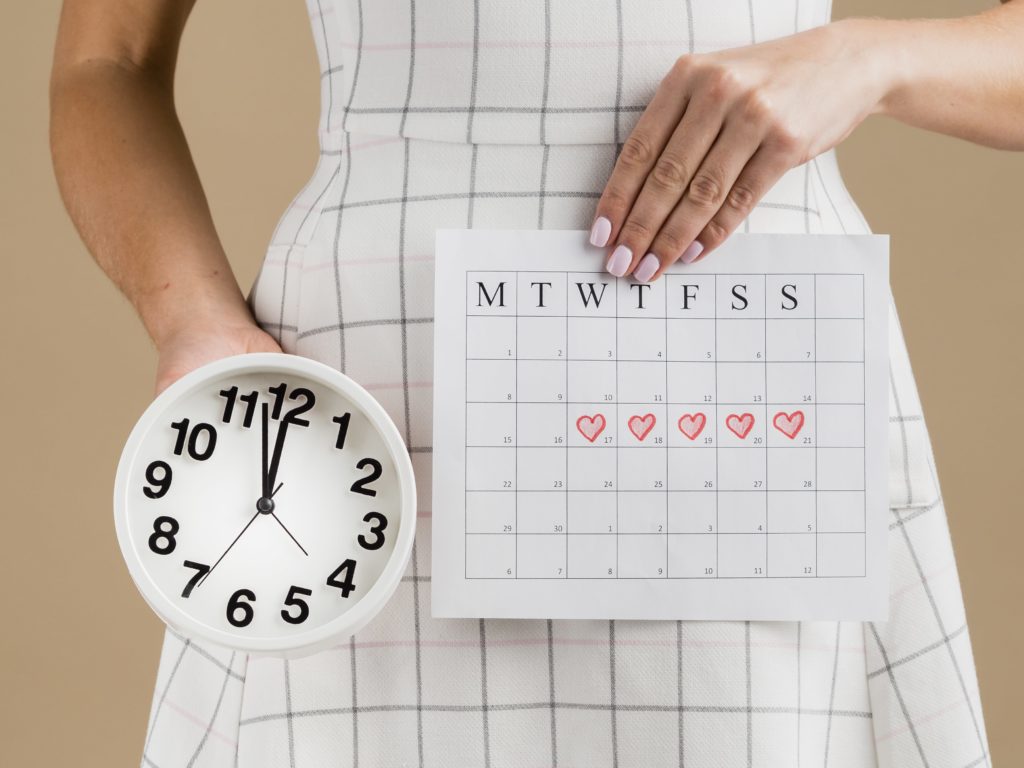 Chica sostiene reloj y calendario de fertilidad