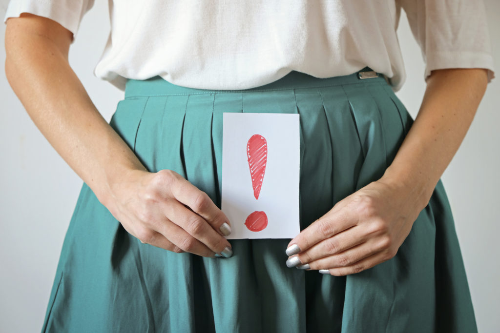 Mujer sosteniendo un papel con una exclamación, signo del sangrado de implantación