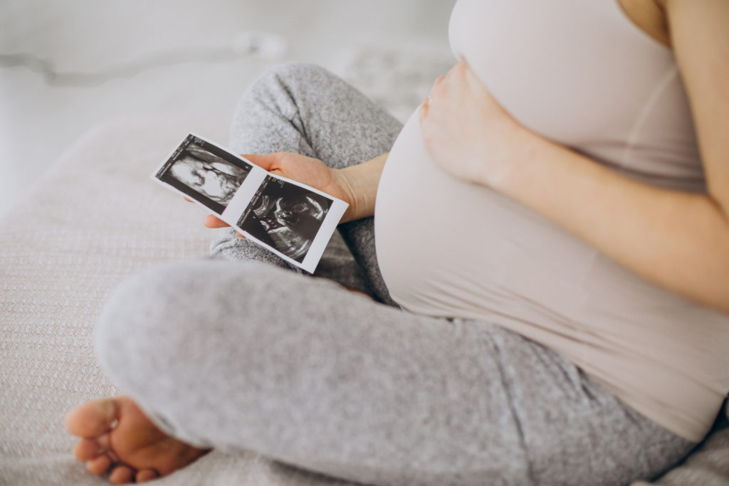 Mujer embarazada observando la ecografía de su bebé después del sangrado de implantación