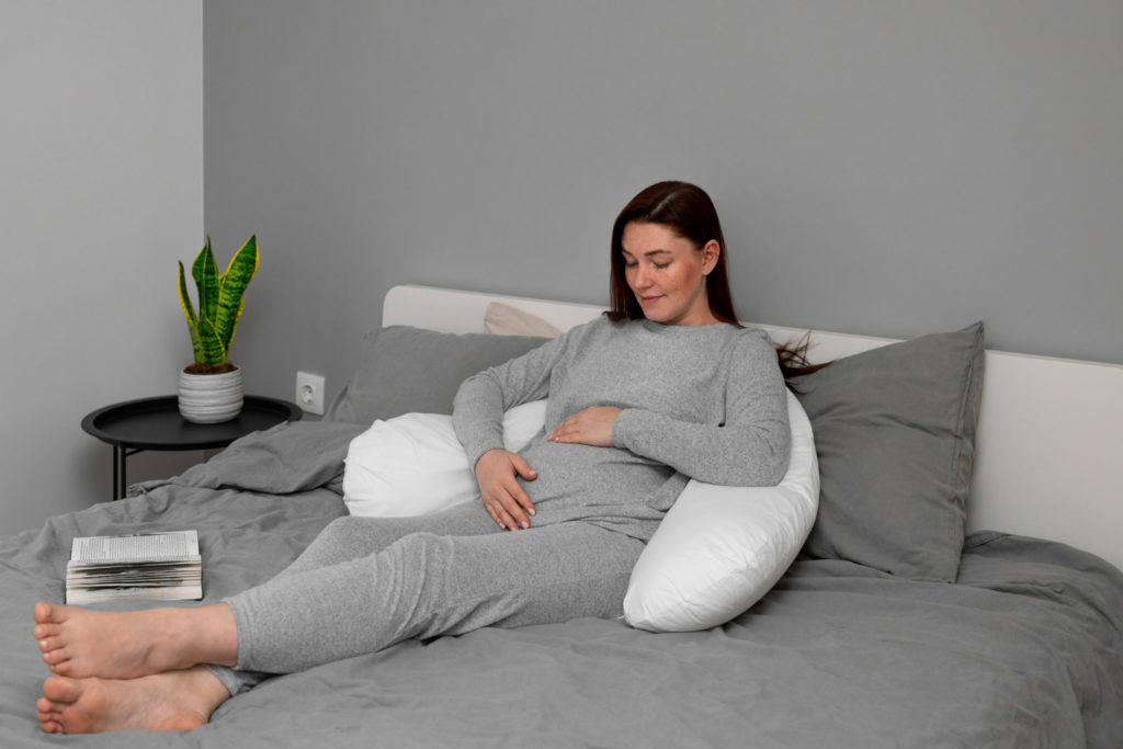Mujer embarazada acostada en una cama en pijama después de experimentar flujo en los primeros días embarazo