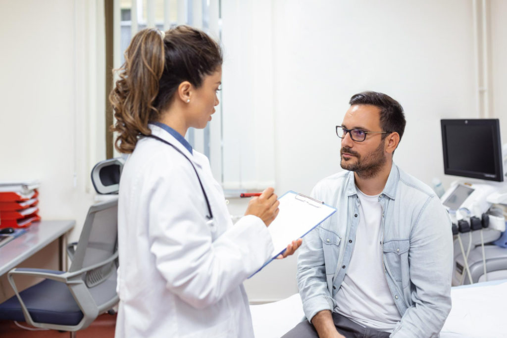 Hombre en consulta médica preguntándole a doctora si tiene teratozoospermia
