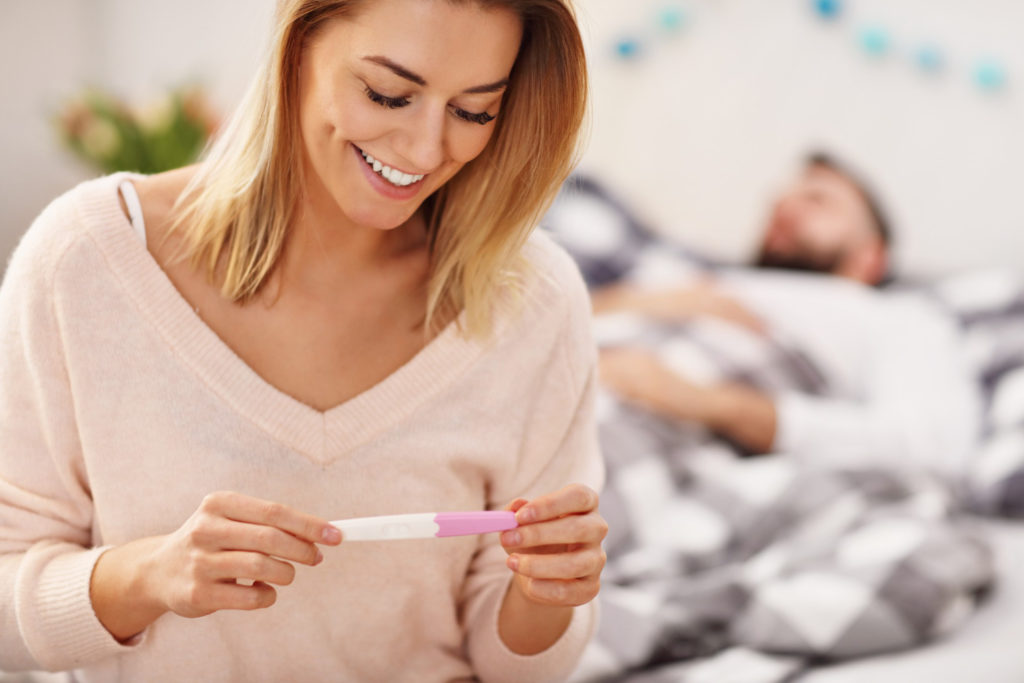 Mujer con test de embarazo positivo preguntandose si se puede estar embarazada y tener la regla abundante