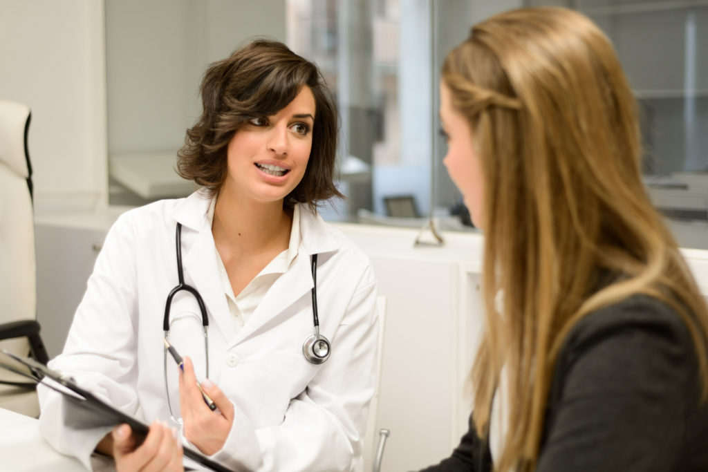 Mujer en consulta mientras la doctora le explica que tiene progesterona baja