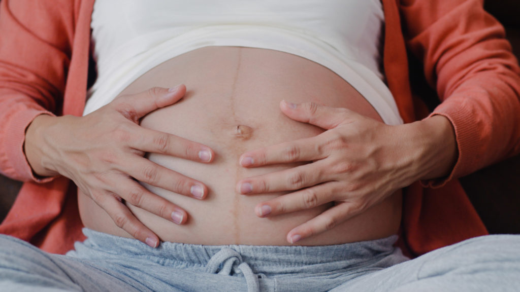 Mujer acariciando la barriga de embarazada después de tener toxoplasmosis en el embarazo