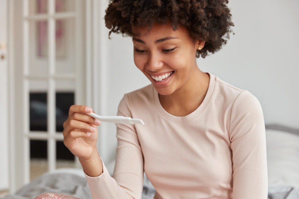 Mujer contenta observando un test de ovulación