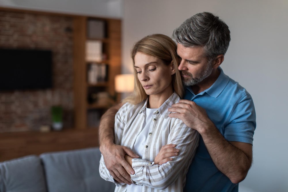Mujer y hombre abrazados preocupados por los 34 síntomas de la premenopausia