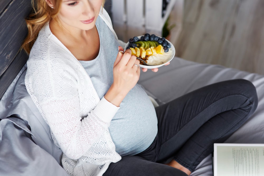 Mujer embarazada comiendo un bol de frutas para cuidar su microbioma