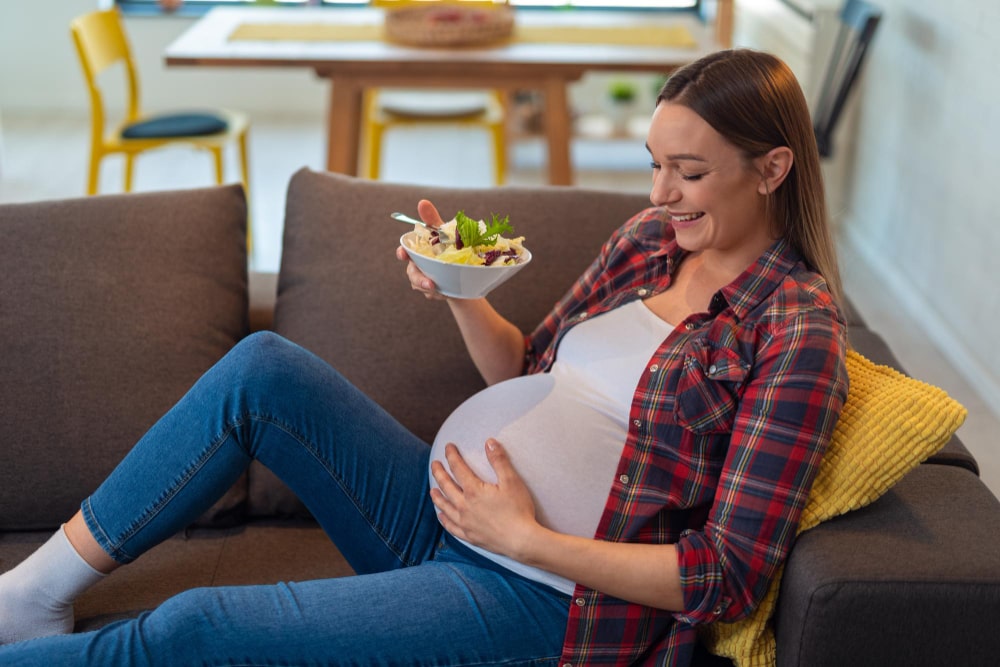 Mujer embarazada tomandose una ensalada para cuida su microbiota