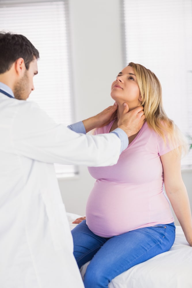 Médico comprobando en el cuello de la paciente si hay relación entre hipotiroidismo y embarazo