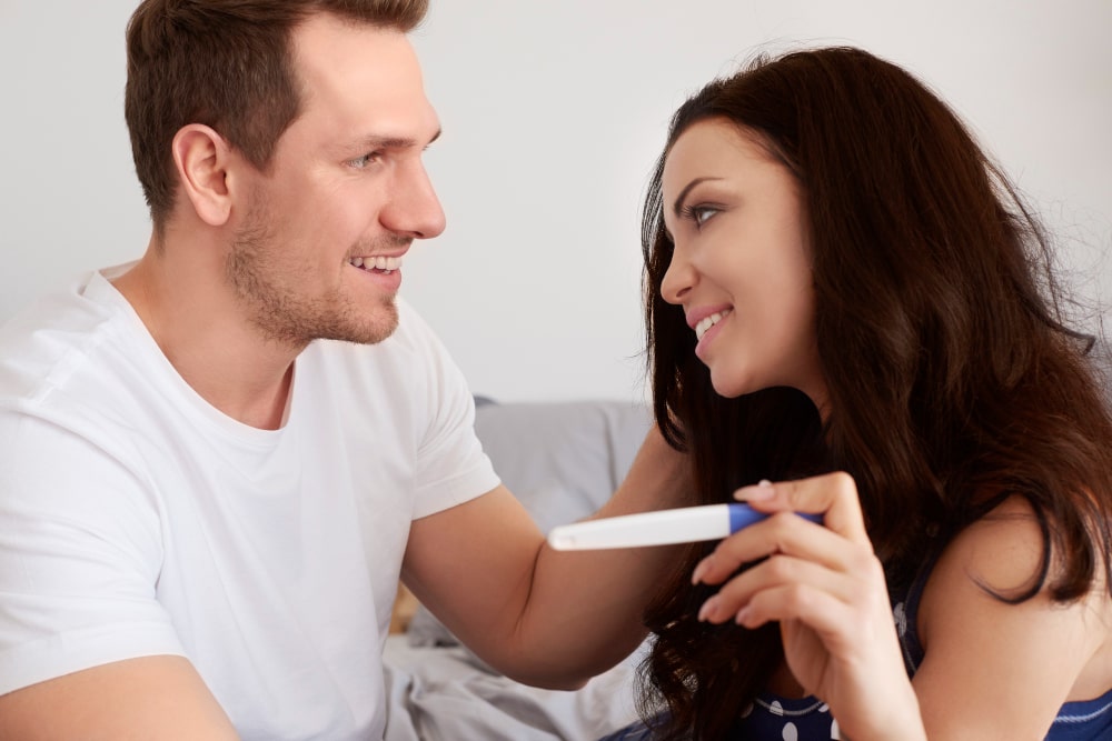 Mujer y hombre teniendo sosteniendo una prueba de embarazo después de evitar los días imposibles para quedar embarazada