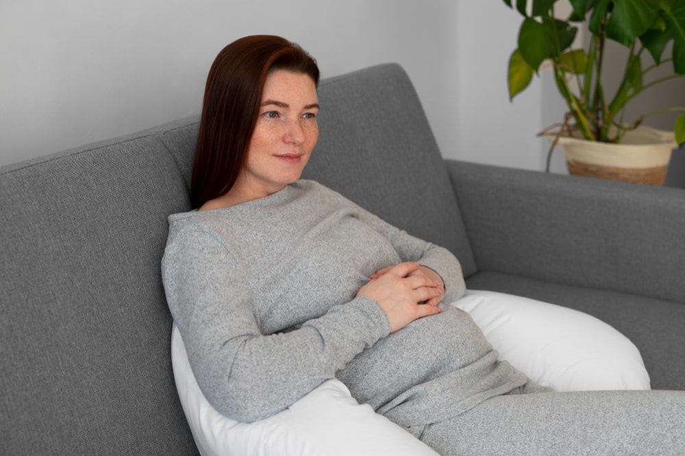 Mujer embarazada en el sofá después de sentir los síntomas de embarazo a los 7 días