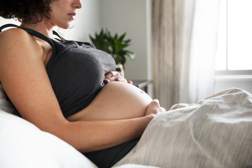 Mujer embarazada en la cama después de fiv positiva a la primera