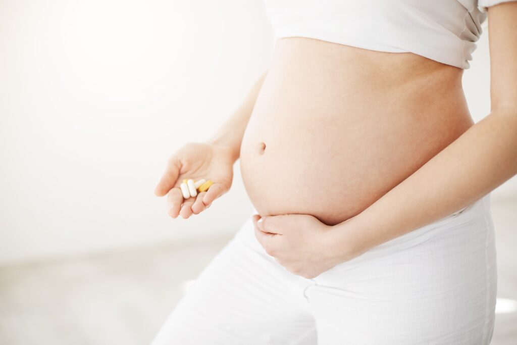 close-up-soon-be-happy-mother-holding-belly-prenatal-pills-vitamins-minerals-waiting-healthy-baby-prenatal-concept-high-key-min Salud reproductiva