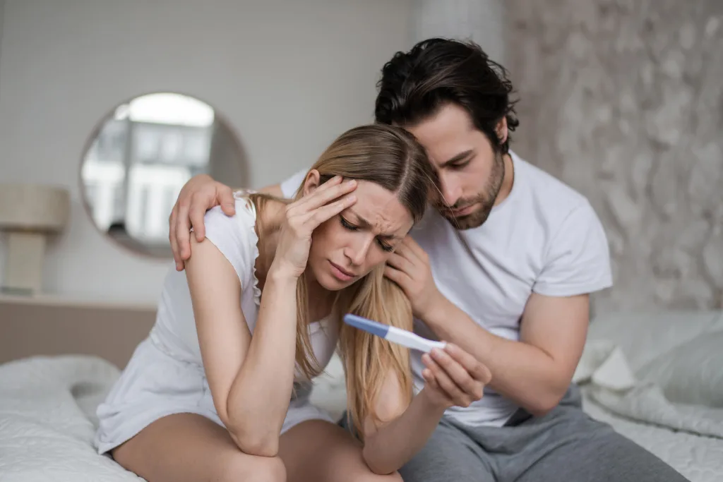 upset-young-husband-comforting-his-depressed-young-wife-with-negative-pregnancy-test-bed-home-min disruptores endocrinos y fertilidad